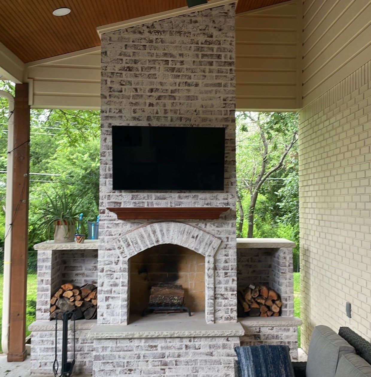 Custom brick outdoor fireplace with TV mount and wood storage